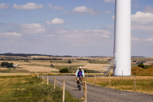 French cyclist near wind turbine at Cros de Georand, Ardeche, France, Massif Centrale, Vestas V47. Windrad mit Radfahrer © Paul Gipe CC BY-SA 4.0 Wikimedia Commons